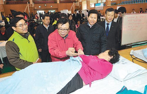 농업인행복버스 사업 출범식에 참석한 이동필 농림축산식품부 장관(왼쪽에서 두 번째)과 최원병 농협중앙회장(왼쪽에서 세 번째)이 물리치료를 받는 여성과 대화를 나누고 있다. 농협중앙회 제공