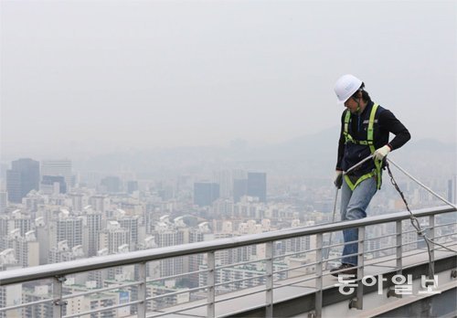 지난달 29일 오전 8시 서울 강남구 아셈타워에서 본 스카이라인. 옥상 난간에 선 외벽 유리 청소업체 직원 뒤로 보이는 강남 일대가 뿌옇다. 어린이, 노약자는 물론이고 외부 작업자들에게 황사와 미세먼지는 공포의 대상이 되고 있다. 김재명 기자 base@donga.com