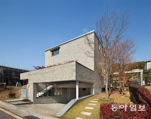 남향인 ‘계수나무집’의 외관. 집 앞과 뒤의 높이 차를 활용해 지하에 주차장을 두고 동쪽에 널찍한 정원을 조성해 가로수 크기의 계수나무를 심었다. 주차장 위는 테라스인데 벽 쪽으로 심어놓은 남천이 겨울에도 붉은 잎으로 멋진 조경을 선사한다. 윤준환 사진작가 제공