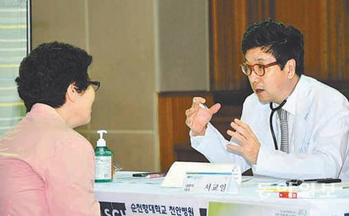 순천향대 서교일 총장(내분비내과 전문의·오른쪽)이 12일 충남 아산시 아산고 체육관에서 한 환자와 상담하고 있다. 순천향대 제공