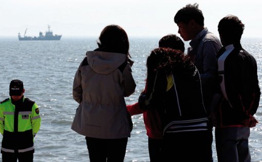 여객선 세월호 침몰 사고 발생 7일째인 4월 22일 전남 진도군 팽목항 선착장에서 한 실종자 가족이 친지들의 위로를 받고 있다.