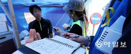 15일 전남 진도군 팽목항에서 세월호 사고 추모기록 보존 자원봉사단원들이 이곳에서 일하는 다른 자원봉사자들의 증언을 기록하고 있다. 이 기록물들은 사고 발생 1년 뒤인 내년 4월 16일 온·오프라인에서 일반에 공개될 예정이다. 진도=김미옥 기자 salt@donga.com