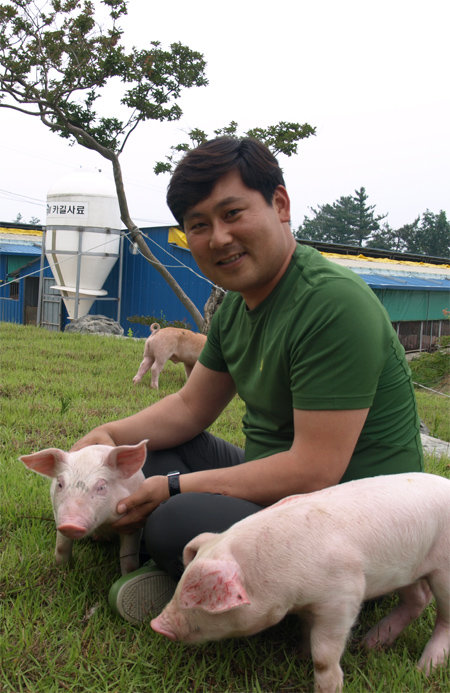 건강한 돼지를 키우는 ‘강산이야기’의 대표 강민구씨가 잔디밭에서 자신이 키우는 돼지들과 포즈를 취했다. 강민구 씨 제공