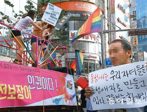 성소수자의 인권을 보호하자는 퀴어문화축제와 이에 반대하는 보수단체의 맞불집회가 7일 오후 서울 서대문구 신촌로 일대에서 동시에 열렸다. 왼쪽 무대 위에서 축제 참가자들이 동성애자의 인권 보호 등을 외치자 오른쪽에 반대 측 단체 회원으로 보이는 남성이 피켓을 들고 시위를 하고 있다. 박영대 기자 sannae@donga.com