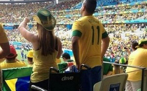 13일(한국시간) 브라질-크로아티아의 개막전이 열린 상파울루 경기장 휠체어좌석에서 두 젊은 남녀가 벌떡 일어나 브라질을 응원하고 있다. 사진출처｜더 텔레그래프 트위터
