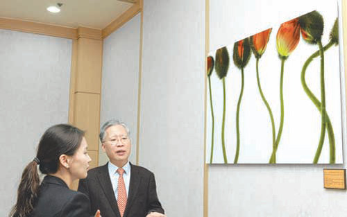 강민구 창원지방법원장(오른쪽)이 119호 소년법정에 걸린 박시호 행복경영연구소 이사장의 사진작품을 방문객에게 설명하고 있다. 창원지법 제공