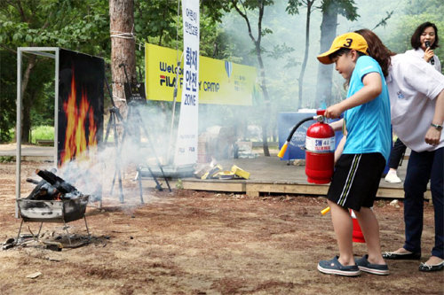 6월 14일 경기 가평군의 한 캠핑장에서 열린 ‘휠라 패밀리 캠프’에서 한 어린이가 소화기 작동 실습을 하고 있다. 휠라코리아 제공