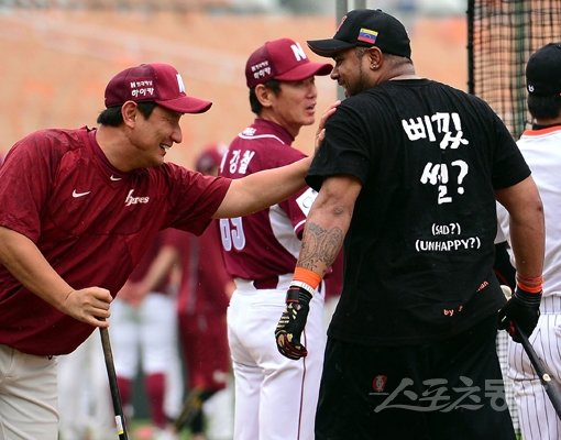 롯데 외국인 투수 유먼이 동료들에게 자비를 들여 제작한 티셔츠를 선물했다. 15일 사직구장에서 부산 사투리가 적힌 티셔츠를 입은 히메네스(왼쪽)와 넥센 심재학 주루코치가 얘기를 나누고 있다. 사직｜김종원 기자 won@donga.com 트위터@beanjjun