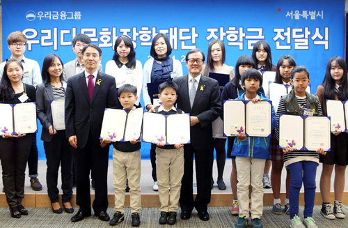 우리금융그룹 이순우 회장(가운데)이 작년 열린 다문화가정 대학생 장학금 전달식에서 학생들에게 장학금을 전달한 뒤 축하해주고 있다. 우리금융지주 제공