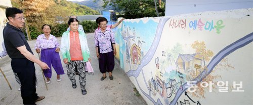 전남 함평군 해보면 산내리 할머니들과 잠월미술관 김광옥 관장(왼쪽)이 벽화를 보며 골목길을 한가롭게 걷고 있다. 골목길 벽화는 할머니들과 작가들이 함께 그렸다. 함평=박영철 기자 skyblue@donga.com