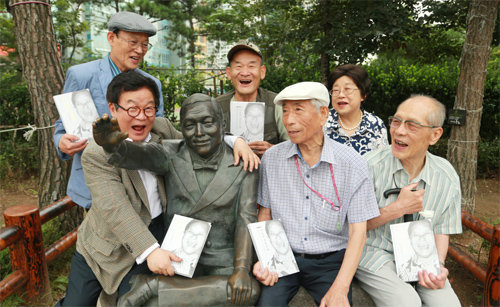 중구토박이회 회원들이 서울 중구 다산교 ‘장소팔 동상’ 앞에서 새로 펴낸 만담 책자를 들고 환하게 웃고 있다. 앞줄 왼쪽이 만담가 장소팔의 아들 장광팔 씨다. 중구 제공