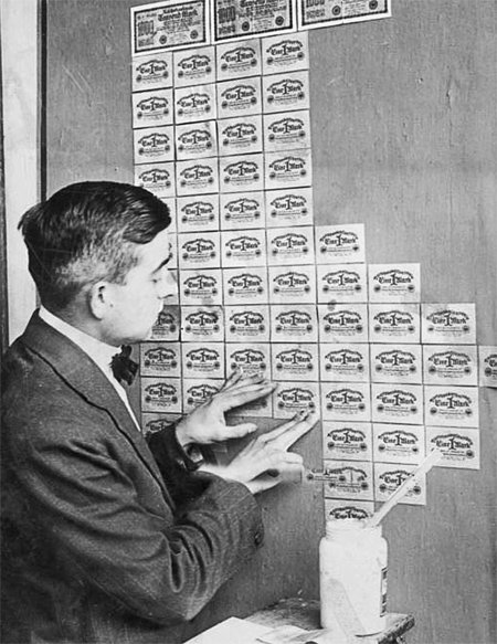 제1차 세계대전 이후 바이마르 공화국에서 한 독일인이 가치가 폭락한 지폐를 벽지로 바르고 있다. 당시 엄청난 인플레이션으로 지폐로 벽지를 사는 것보다 지폐를 벽지로 쓰는 것이 더 저렴했다. 21세기북스 제공