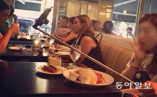 외국의 한 식당에서 한국여성이 셀카봉을 꺼내 자신의 모습을 찍고 있다. 인터넷 캡처