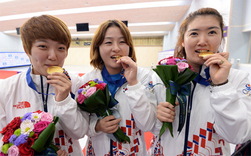 金 맛 어때요? 22일 인천 옥련국제사격장에서 열린 사격 여자 25m 권총 단체전에서 우승한 한국의 김장미, 이정은, 곽정혜(왼쪽부터)가 시상대에서 금메달을 무는 포즈를 취하고 있다. 인천=사진공동취재단