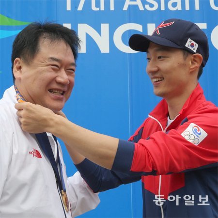 ‘셔틀콕 끝판왕’ 이현일(오른쪽)이 중국을 꺾고 12년 만에 따낸 배드민턴 단체전 금메달을 24일 이득춘 감독에게 걸어주고 있다. 인천=홍진환 기자 jean@donga.com