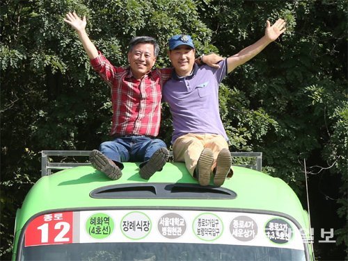 세계여행을 떠나는 오권태 씨(왼쪽)와 임택 씨가 여행을 함께할 종로 12번 마을버스 ‘은수’ 위에 앉아 손을 흔들고 있다. 박영대 기자 sannae@donga.com