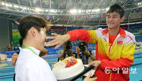 26일 남자 혼계영 400m 시상식을 마친 박태환(왼쪽)에게 라이벌인 중국의 쑨양이 생일 케이크를 선물한 뒤 얼굴에 크림을 묻히고 있다. 인천=홍진환 기자 jean@donga.com