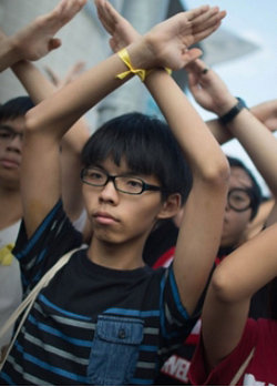 1일 국경일을 맞아 홍콩에서 국기 게양식이 진행되는 동안 조슈아 웡 군(가운데) 등 학생 시위대가 뒤돌아서서 양손을 머리 위로 들어올려 ‘X’자를 만들고 있다. 사진 출처 CNN