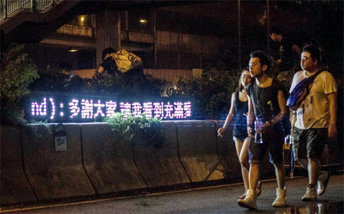홍콩 민주화 시위 참가자들이 발광다이오드(LED) 게시판에 뜬 세계 각국의 응원 메시지를 바라보며 걸어가고 있다. 사진 출처 시민단체 ‘스탠드바이유’