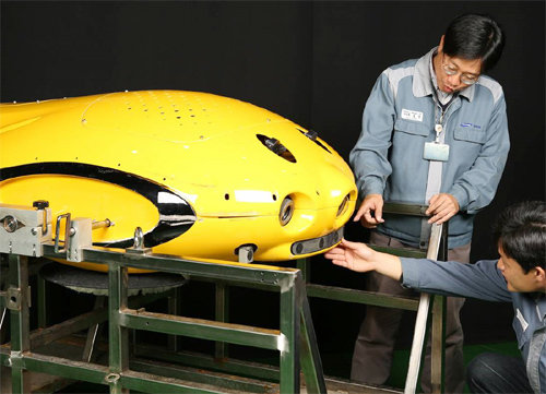 삼성중공업이 물에 잠긴 선체 하부에 붙어 유기물을 제거하는 수중 선체청소로봇을 개발했다. 사진은 연구원들이 수중 선체청소로봇을 점검하는 모습. 삼성중공업 제공