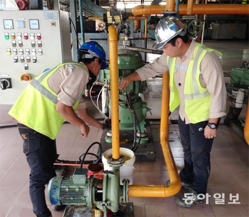 LG상사 팜오일 생산 공장에서 한국인 직원인 김교윤 씨(오른쪽)가 현지 직원과 함께 갓 짜낸 팜오일의 상태를 확인하고 있다.