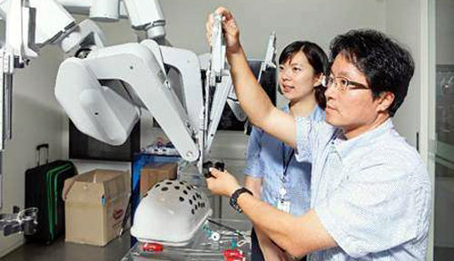 본보 이진한 기자가 로봇트레이너 김미연 씨(왼쪽)의 도움으로 ‘다빈치 SI’의 로봇팔을 만지면서 실습을 하고 있다.