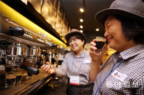 바리스타 과정 중 커피머신의 사용법을 배우며 직접 추출한 커피의 향을 맡고 있다.