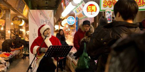 경기 광명시 광명전통시장에서 지난해 크리스마스 무렵 열린 ‘한평 스테이지 게릴라 콘서트’에서 산타 복장을 한 음악인이 우쿨렐레를 연주하며 노래하고 있다. 광명전통시장 제공