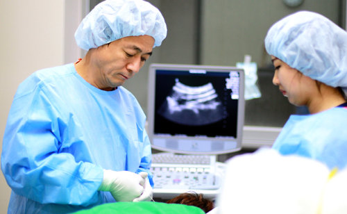 안강병원 안강 원장(왼쪽)이 직접 개발한 특수치료법 FIMS 시술을 시행하고 있다. 안강병원 제공