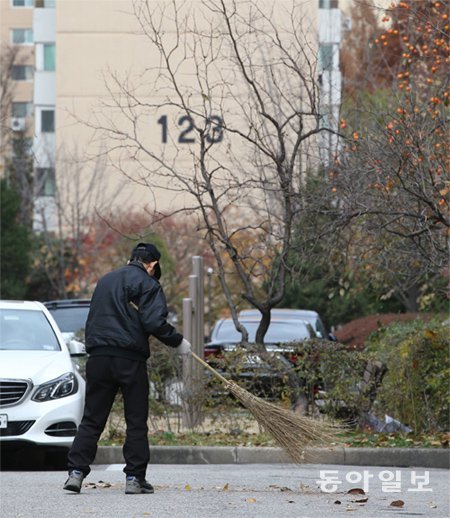 한 경비원이 25일 서울 강남구의 한 아파트에서 떨어진 은행잎을 치우고 있다. 50대 경비 근로자가 분신자살한 이 아파트의 경비 근로자 78명은 용역업체로부터 해고 예고 통보를 받았다. 박영대 기자 sannae@donga.com