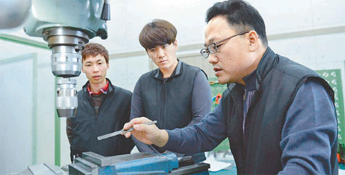 비즈엔몰드에 취업해 일과 학습을 병행하고 있는 길현석 씨(왼쪽)와 김일만 씨(가운데)가 국내 최연소 기술명장 원용기 씨(오른쪽)에게서 기계 사용 기술에 대한 교육을 받고 있다. 한국산업인력공단 제공