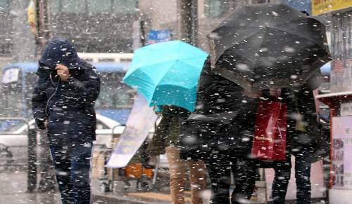 서울에 첫 눈이 내린 1일 오전 시민들이 강풍을 동반한 눈을 맞으며 서울 중구 명동 거리를 지나고 있다. 홍진환 기자