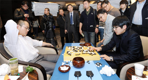 김지석 9단(오른쪽)이 9일 삼성화재배 결승1국에서 불계승을 거둔 뒤 관계자들이 지켜보는 가운데 탕웨이싱 9단과 복기를 하고 있다. 한국기원 제공