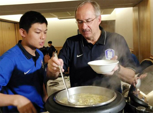 “새해엔 떡국” 울리 슈틸리케 한국 축구 대표팀 감독(오른쪽)이 1일 호주 시드니 숙소에서 대표팀 통역 이윤규 씨의 도움을 받으며 떡국을 뜨고 있다. 대한축구협회 제공