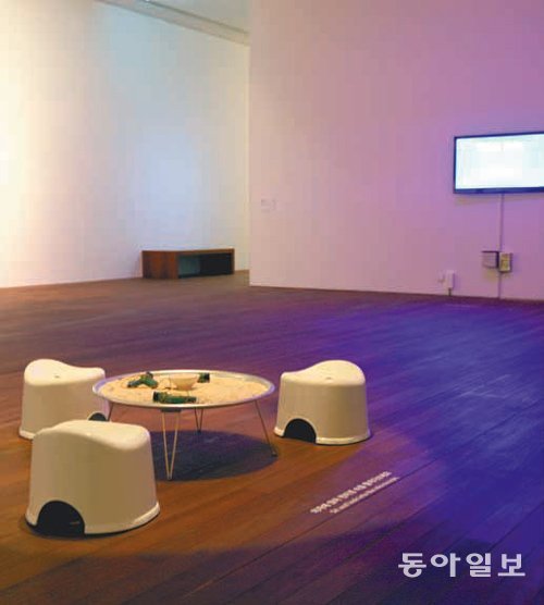 고창선 작가의 ‘빌리브 2015’. 의자에 둘러앉아 현미경으로 쌀알을 관찰하도록 유도한다. 전시실 출구에는 작가가 일방적으로 강요한 이 무의미한 행위를 구경하는 스크린을 설치했다.
손택균 기자 sohn@donga.com