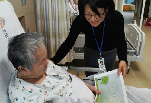 행복요양병원은 환자에게 자존감을 회복시키는 ‘환자 스토리북’을 제작해 선물한다. 병원 직원이 환자에게 스토리북을 전달하고 있다. 강남구립행복요양병원 제공
