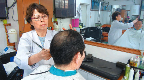 인천 계양구에서 30년째 한진이발관을 운영하고 있는 김화자 원장이 23일 오후 단골손님의 머리를 손질하고 있다. 김 원장은 “지난해 12월 인천시의 도움으로 간판과 실내 인테리어를 바꾼 뒤 젊은 고객도 조금씩 늘고있다”고 말했다. 김영국 동아닷컴 객원기자 press82@donga.com