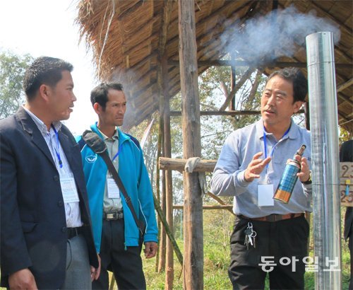 김종복 적정과학기술거점센터 최고기술책임자(오른쪽)가 라오스 시엥무아크 마을 주민들에게 식용유통과 벽돌 등으로 만든 난로를 시연해 보이고 있다.
