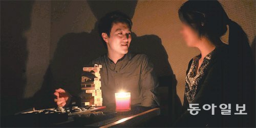 어둠 속에서 즐기는 이색 데이트가 최근 젊은 연인들 사이에서 인기다. 서울 서대문구에 자리한 암흑 콘셉트의 한 카페에서 본보 이철호 기자가 여자친구와 함께 보드게임을 즐기고 있다. 장승윤 기자 tomato99@donga.com