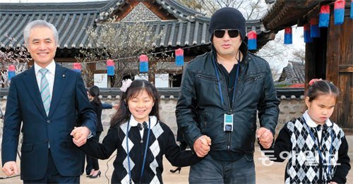 시각장애 어린이의 손을 잡고 한옥마을을 관람하는 박종복 스탠다드차타드은행장(왼쪽)과 배우 김보성 씨(시각장애인연합회 홍보대사).