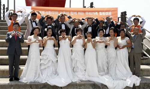 19일 한화생명 ‘우리가족 힐링캠프’에 참가해 제주도에서 결혼식을 올린 만성신부전 환자 부부 8쌍이 손으로 하트를 그리며 환하게 웃고 있다. 한화생명 제공