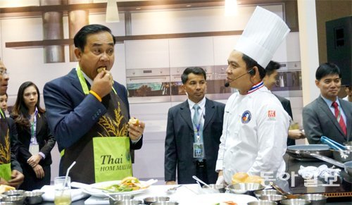 “쌀햄버거 맛있어요” 컨벤션 강연장 바깥에 설치된 요리 부스에서 쁘라윳 짠오차 총리가 유명 태국 요리사가 만든 쌀햄버거를 시식하고 있다. 방콕=전주영 기자 aimhigh@donga.com