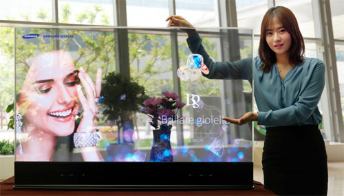 삼성디스플레이가 9일부터 홍콩에서 열린 ‘리테일 아시아 엑스포’에서 세계 최초로 선보인 55인치 투명 유기발광다이오드(OLED) 패널을 모델이 소개하고 있다. 삼성디스플레이 제공