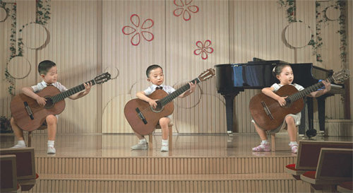 북한의 상류층 자제들이 다니는 평양 경상유치원에서 원생들이 제 몸집만 한 기타를 연주하고 있다. 사진 출처 뉴욕타임스