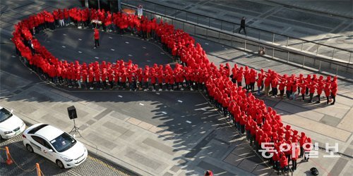2013년 세계 에이즈의 날을 맞아 한국에이즈퇴치연맹이 서울 청계광장에서 마련한 플래시몹 행사에 참여한 청소년들이 에이즈 퇴치 운동의 상징인 빨간 리본을 만들어 보이고 있다. 동아일보DB