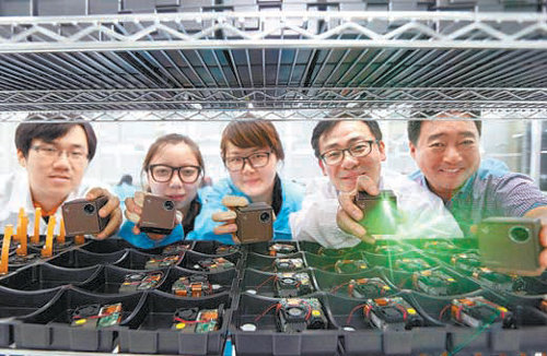 SK텔레콤과 ㈜크레모텍 직원들이 한 손에 쥘 수 있는 초소형 빔 프로젝터인 ‘UO 스마트빔 레이저’를 들고 있다. SK텔레콤 제공