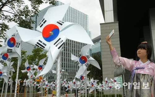 광복 70주년을 열흘 앞둔 5일 오후 서울 광화문 대한민국 역사박물관 앞세 설치된 태극기 바람개비를 배경으로 한복을 입고 경복궁 나들이에 나선 여고생들이 셀프카메라를 찍고 있다. 양회성 기자 yohan@donga.com