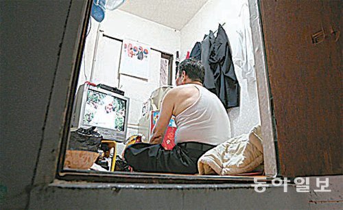 정모 씨가 비좁고 더운 쪽방에서 TV를 보고 있다. 최혁중 기자 sajinman@donga.com