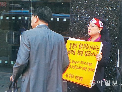 마영애 미주탈북자선교회 대표(오른쪽)가 12일 미국 뉴욕 북한대표부 사무실로 들어서는 안명훈 주유엔 북한대표부 차석대사(등 보인 이)에게 “살인 악마 김정은을 처단하라”라고 외쳤다. 뉴욕=부형권 특파원 bookum90@donga.com