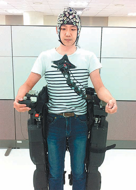 이성환 고려대 교수팀 소속 연구원이 뇌전도측정기를 착용하고 외골격 로봇에 올라탄 모습. 외골격 위에 부착된 LED 전구를 응시하면 뇌파를 해석한 신호를 받아 외골격이 움직인다. 고려대 제공